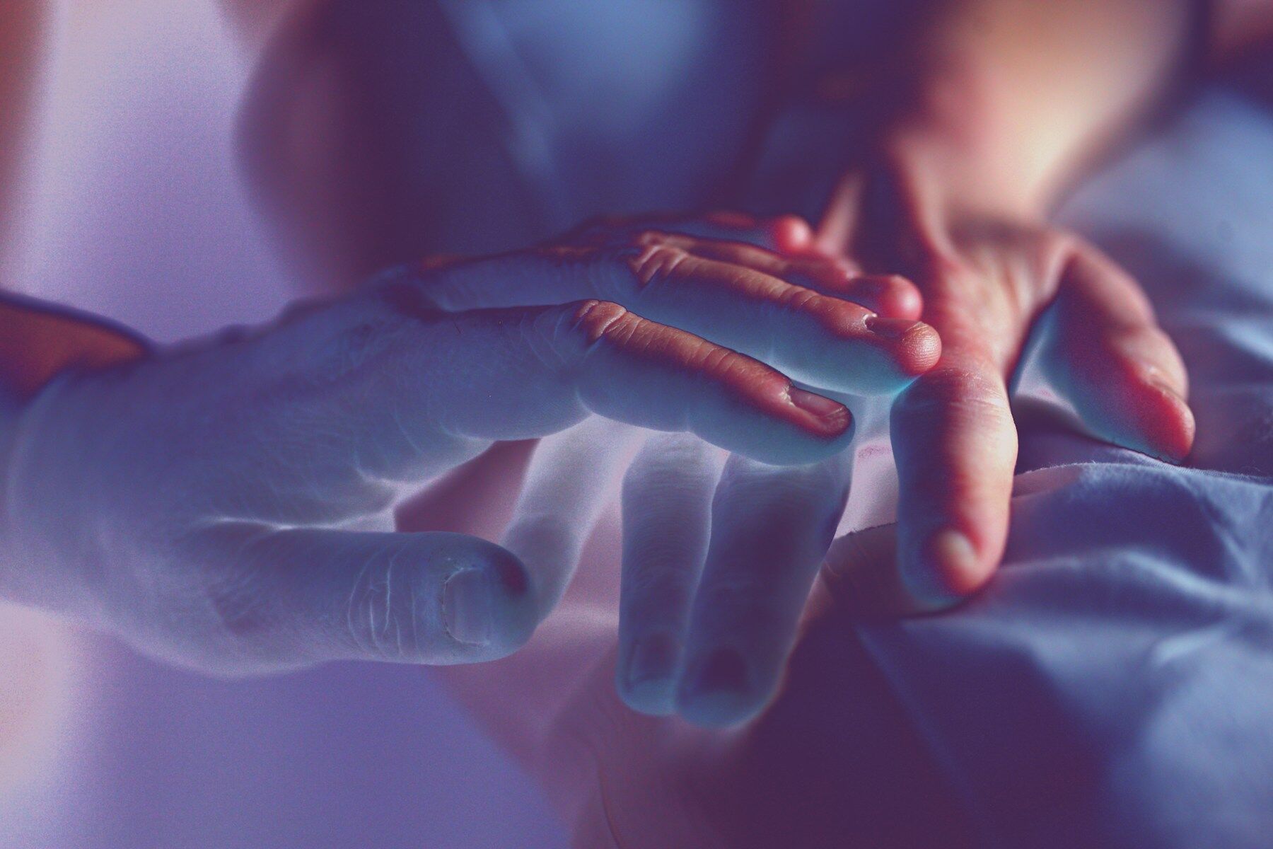 Mains posées doucement l’une au-dessus de l’autre, lumière bleutée et violette