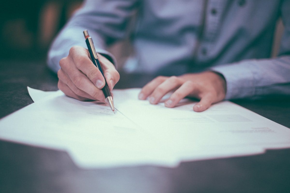 Main d'un avocat annotant un document au stylo, sur un bureau