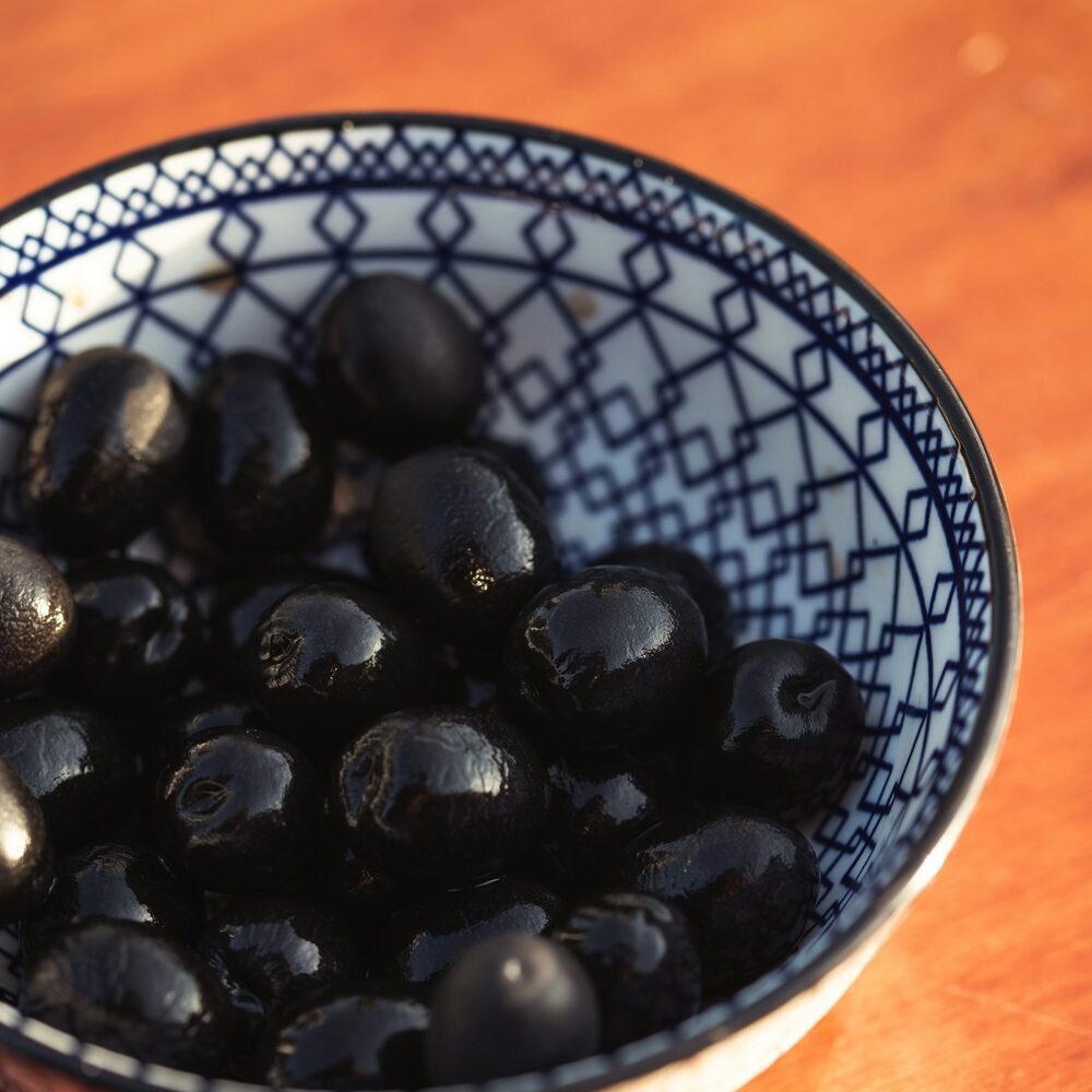 Olives noires ridées dans un bol bleu et blanc
