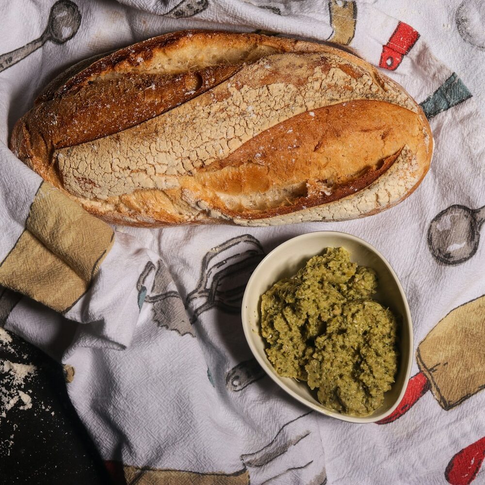 Tapenade verte dans une coupelle, à côté d’un pain de campagne