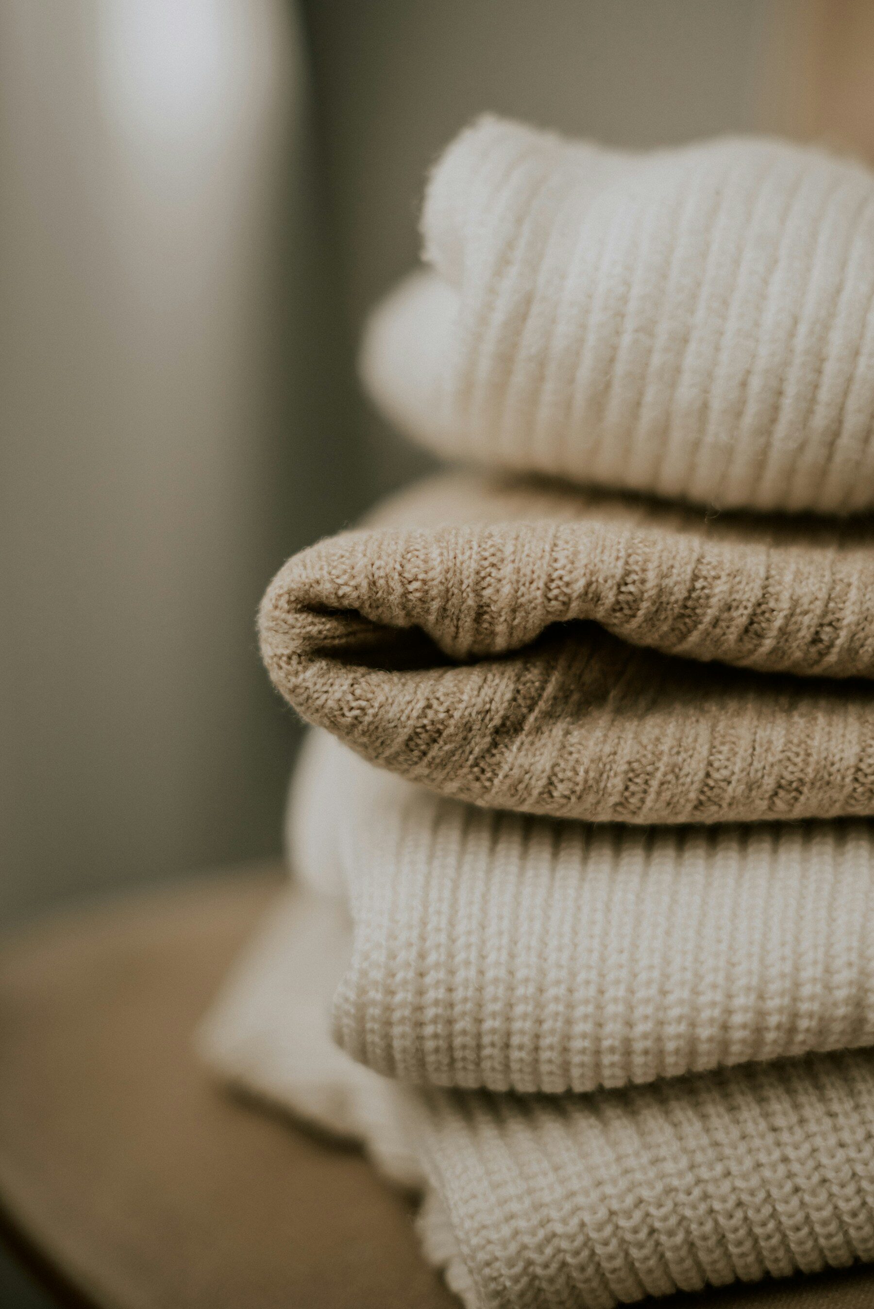 Pile de pulls en maille côtelée, écru et sable