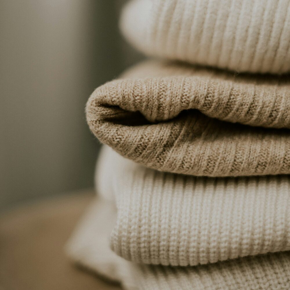 Pile de pulls en maille côtelée, écru et sable