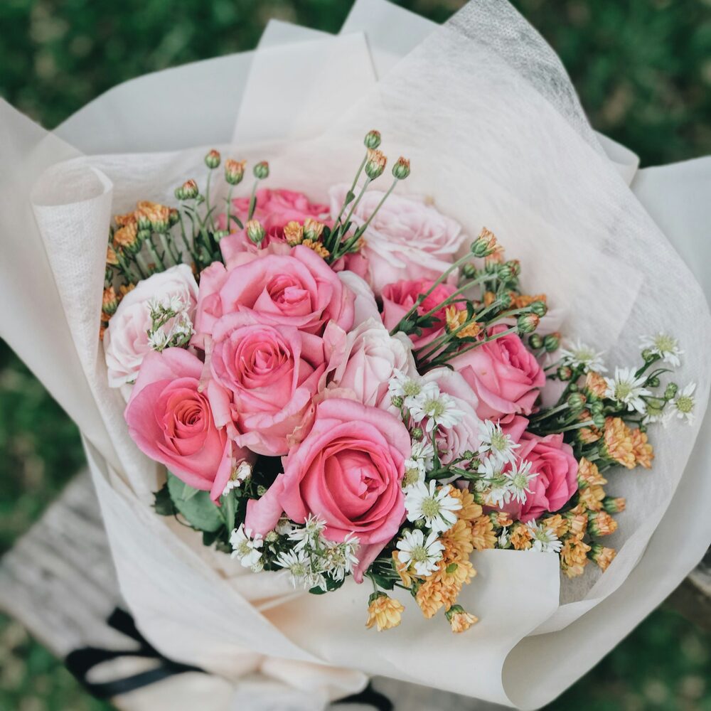 Bouquet de roses roses et de petites marguerites emballé dans un papier crème