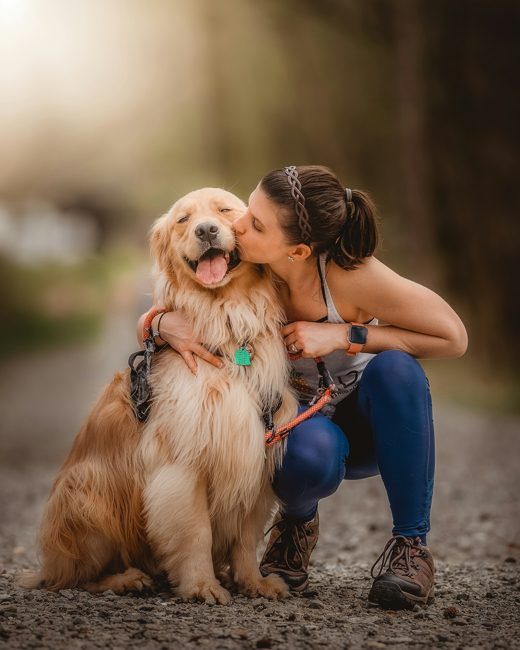 Une adoptante accroupie serre son chien contre elle et l'embrasse sur la tête