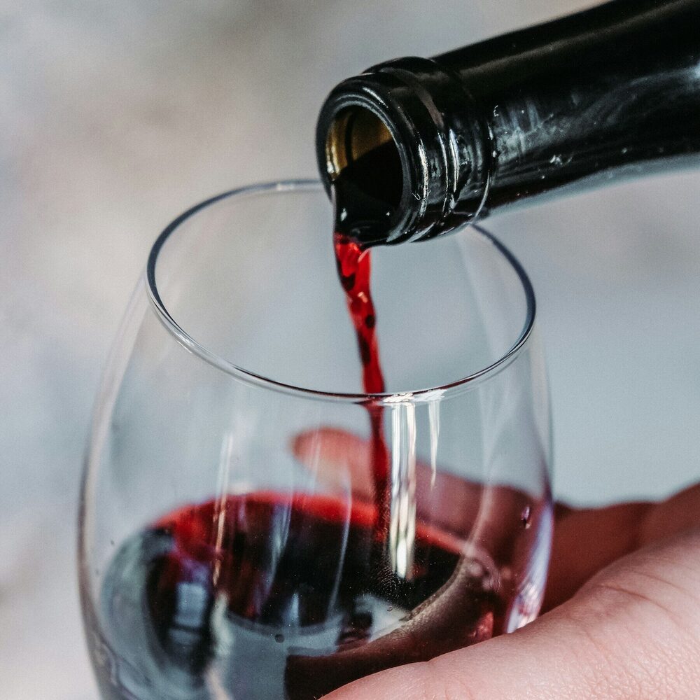 Vin rouge versé dans un verre tenu à la main