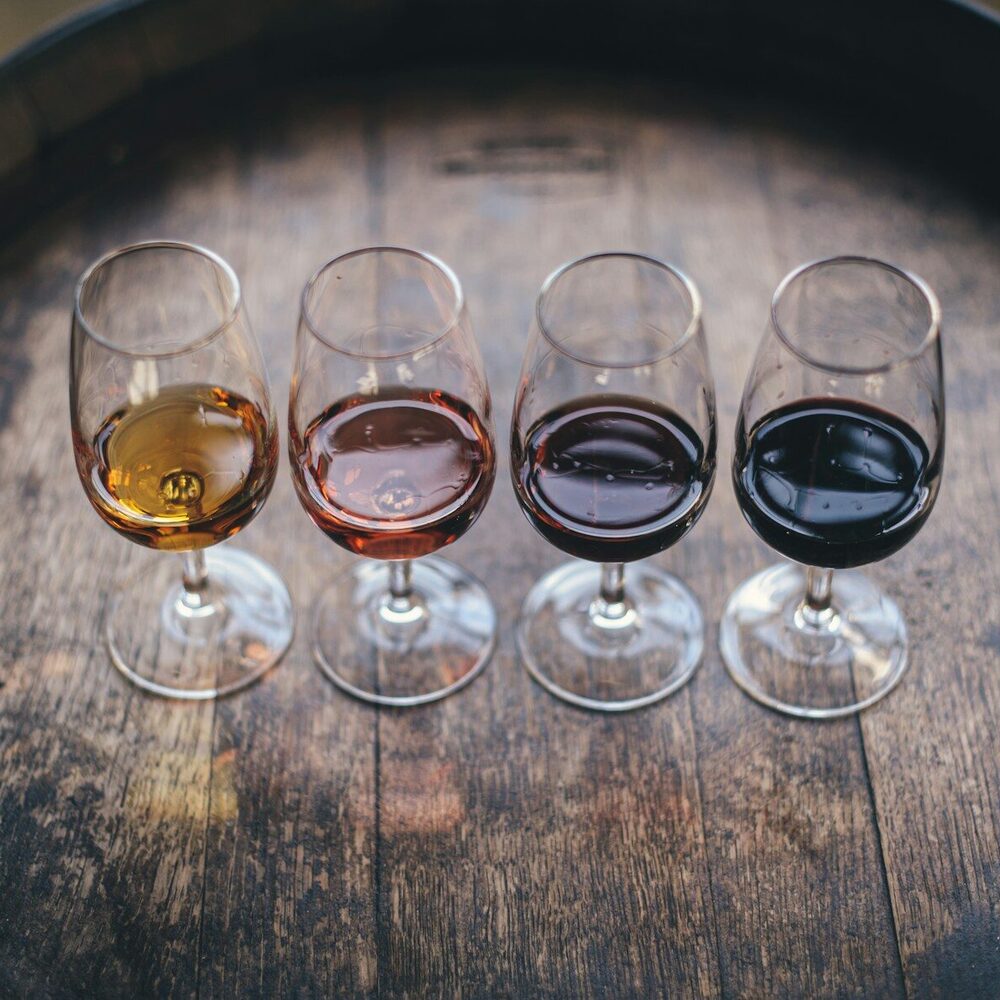 Quatre verres de dégustation, du blanc au rouge, posés sur un fût