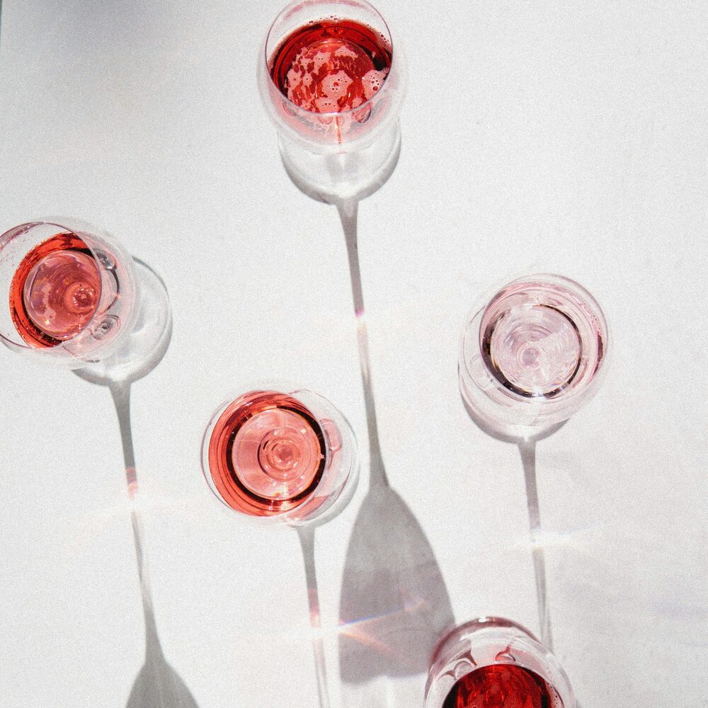 Cinq verres de vin rosé vus de dessus, sur fond blanc