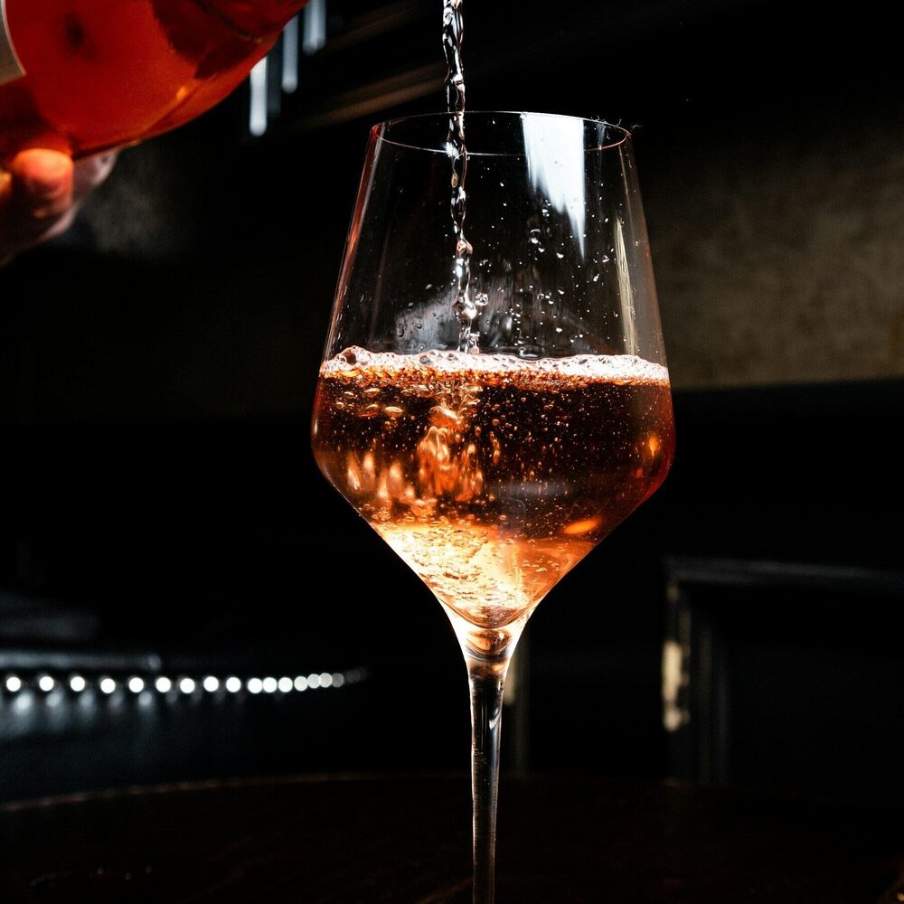Vin rosé versé dans un verre à pied, sur fond sombre