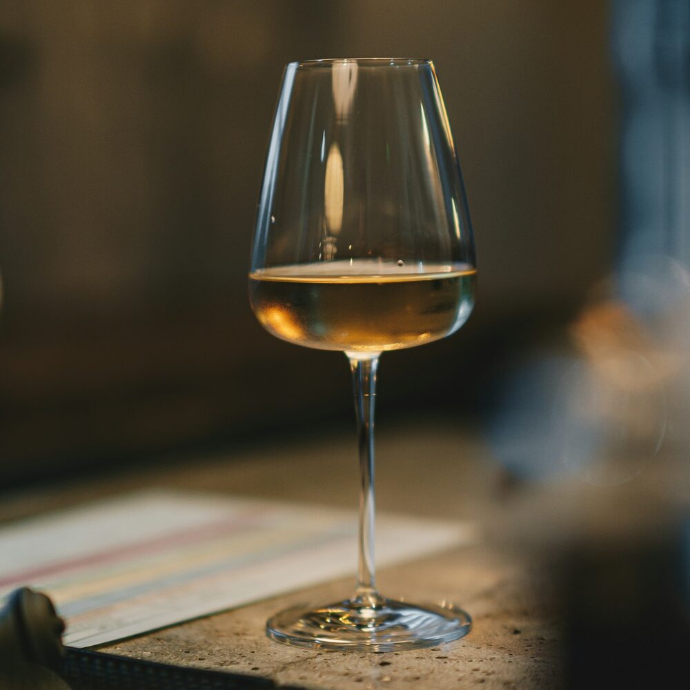 Verre de vin blanc doré posé sur un comptoir, fond sombre