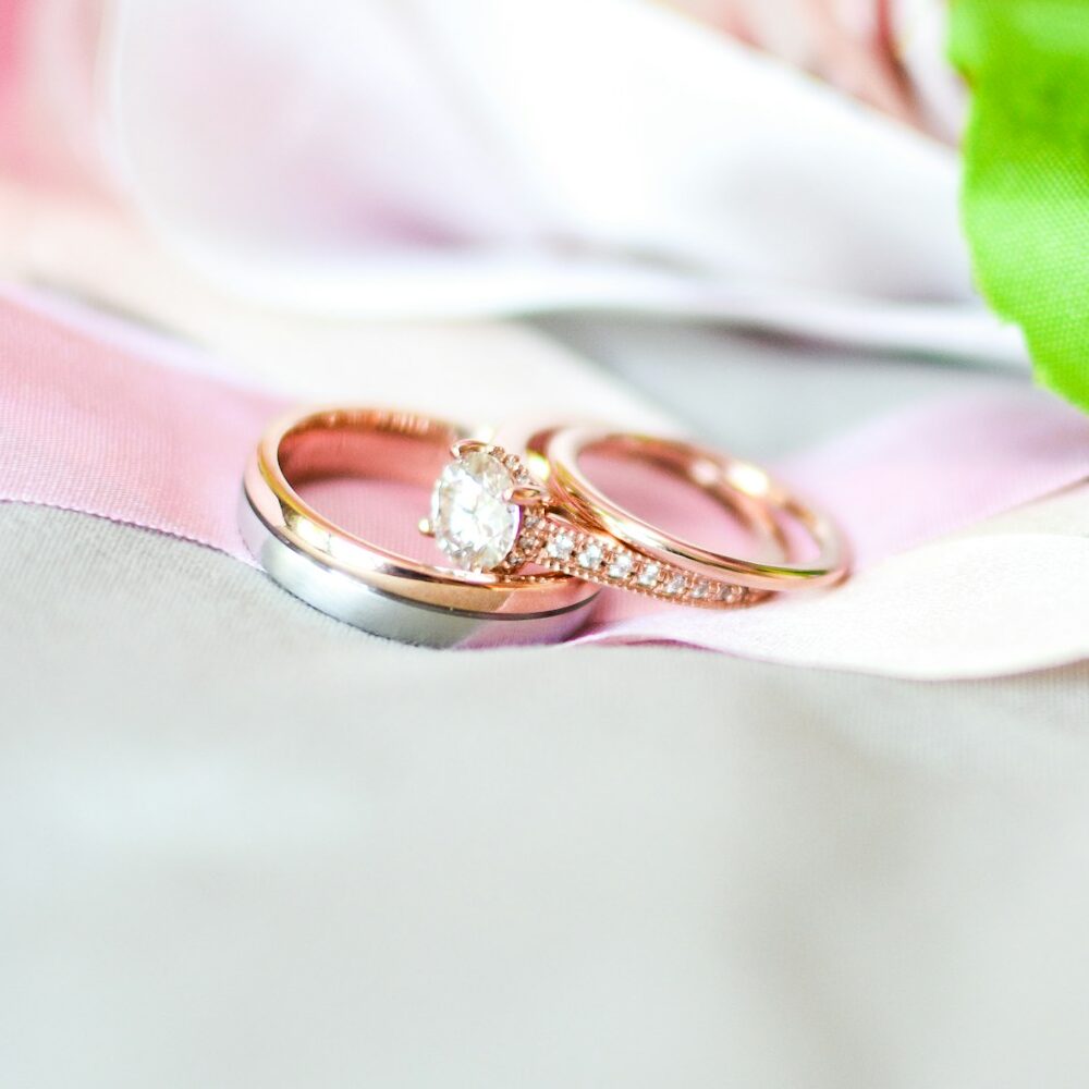 Bague solitaire et alliance fine or rose sur un ruban rose poudré