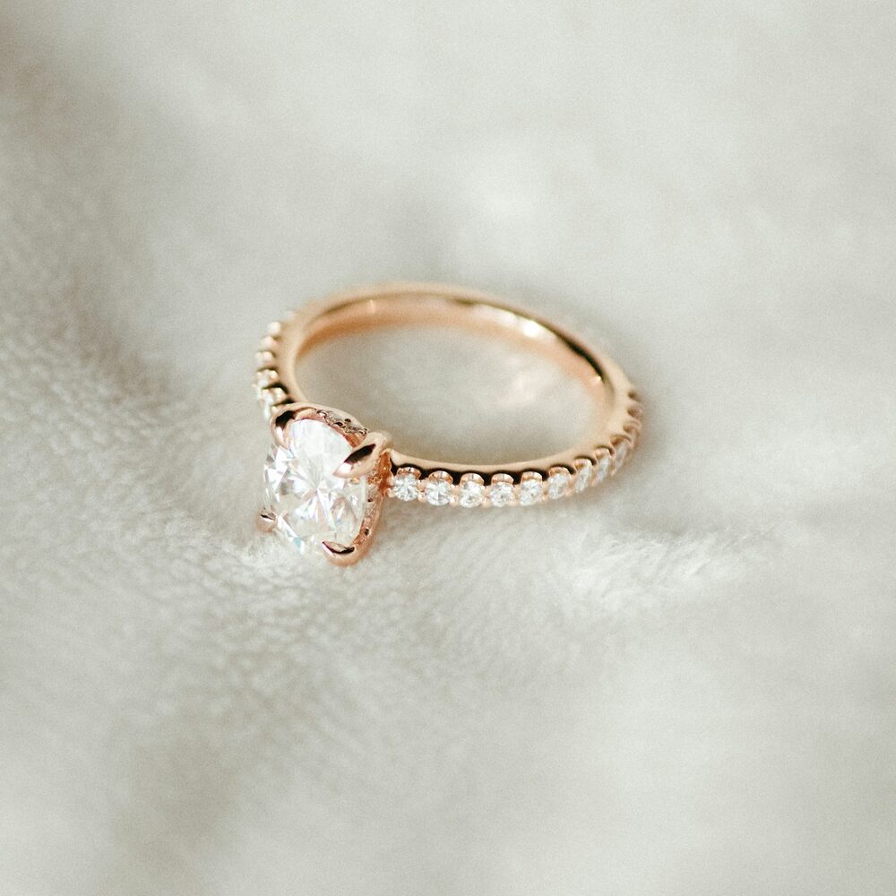Bague or rose à pierre blanche ovale sur tissu blanc