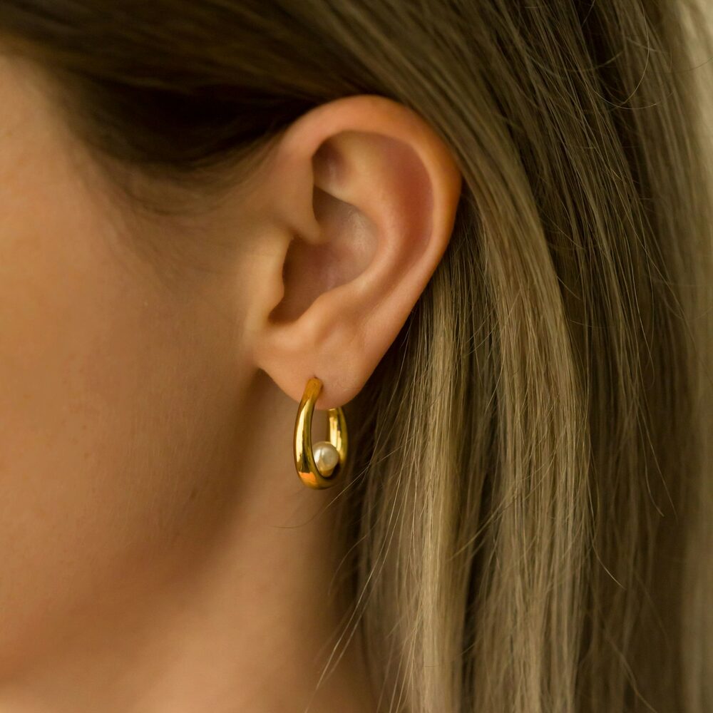 Créole goutte dorée avec une petite perle, portée à l'oreille