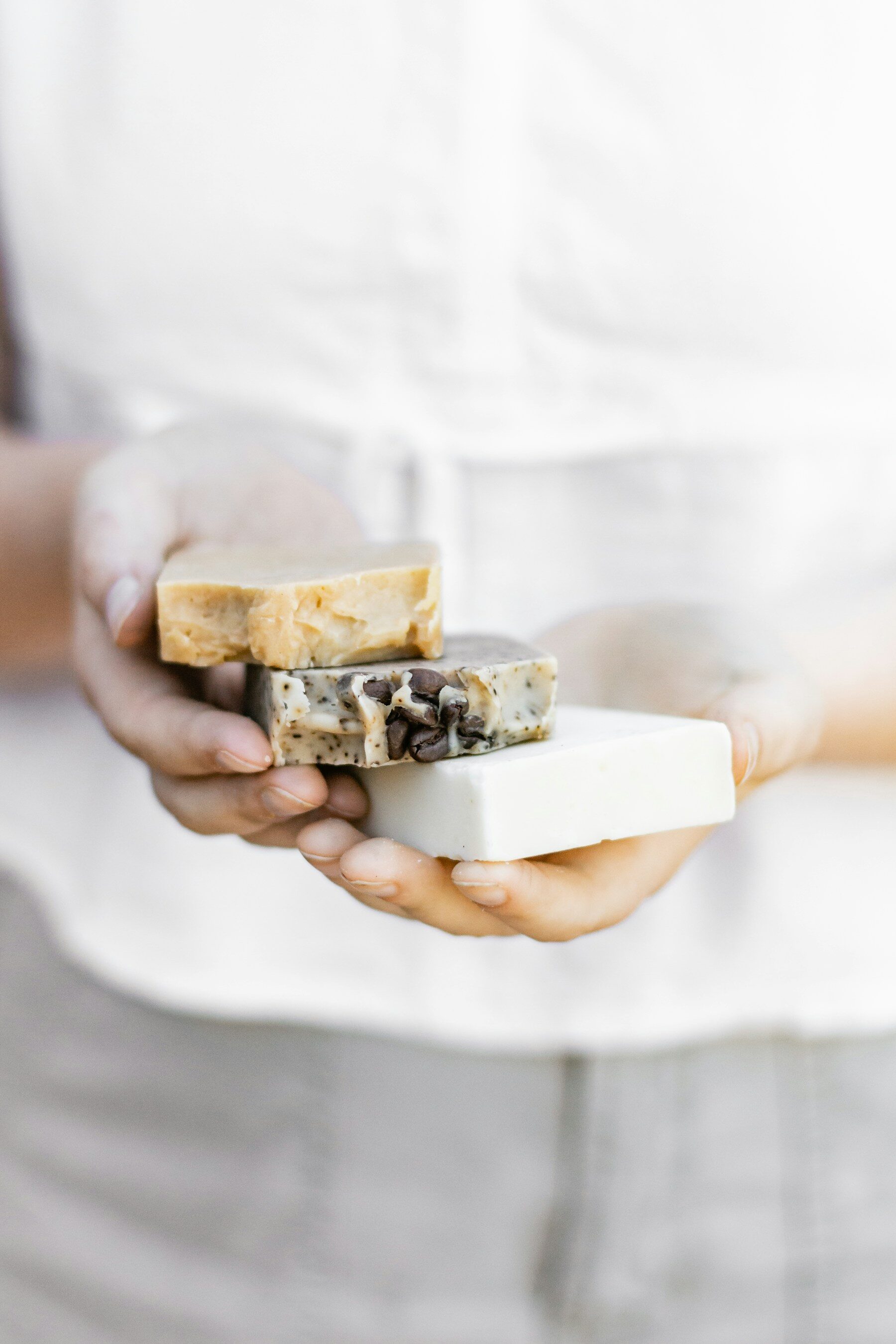 Mains tenant trois savons artisanaux