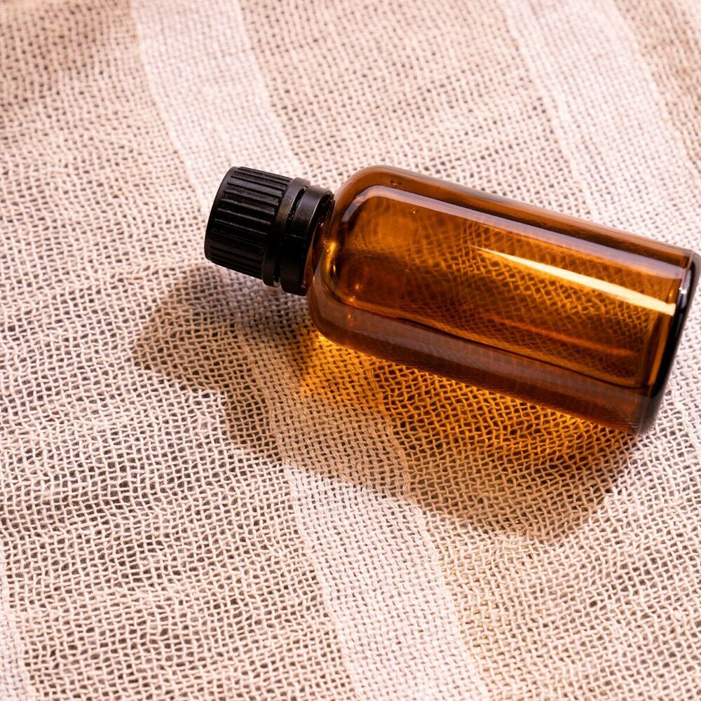 Flacon en verre ambré couché sur une gaze de coton rose
