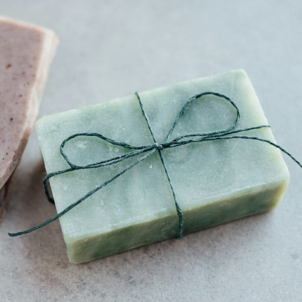 Savon vert à l’argile noué d’une ficelle, sur un fond gris