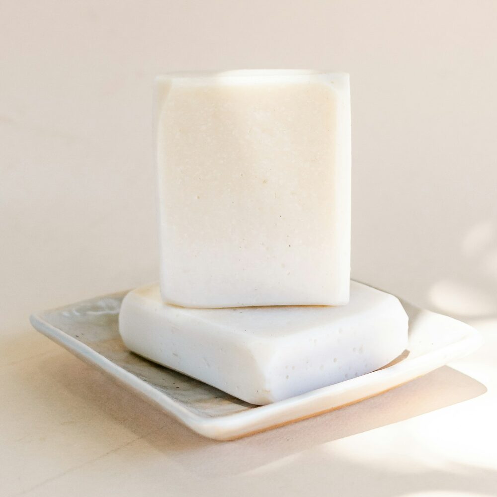 Deux savons blancs posés sur un porte-savon en marbre