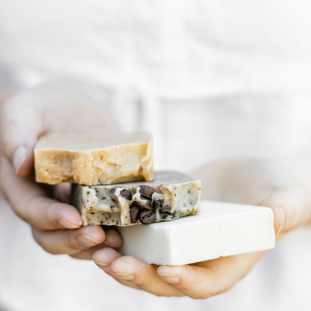 Mains tenant trois savons artisanaux