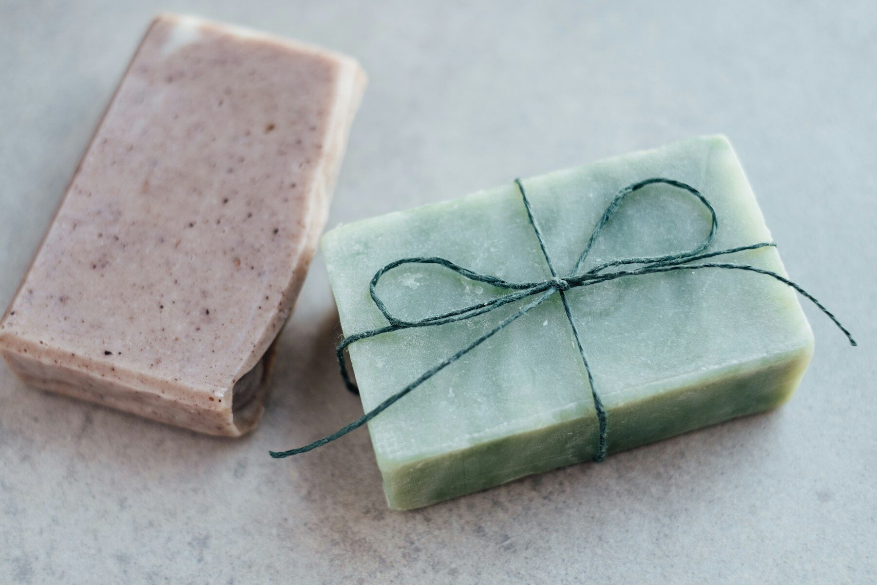 Savon vert noué d’une ficelle, à côté d’un savon rose à l’argile