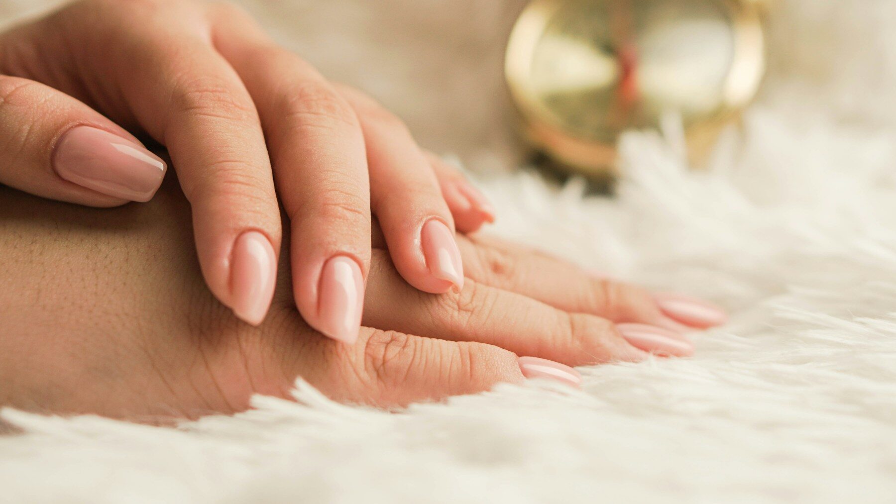 Ongles nude sur une main posée sur une fourrure