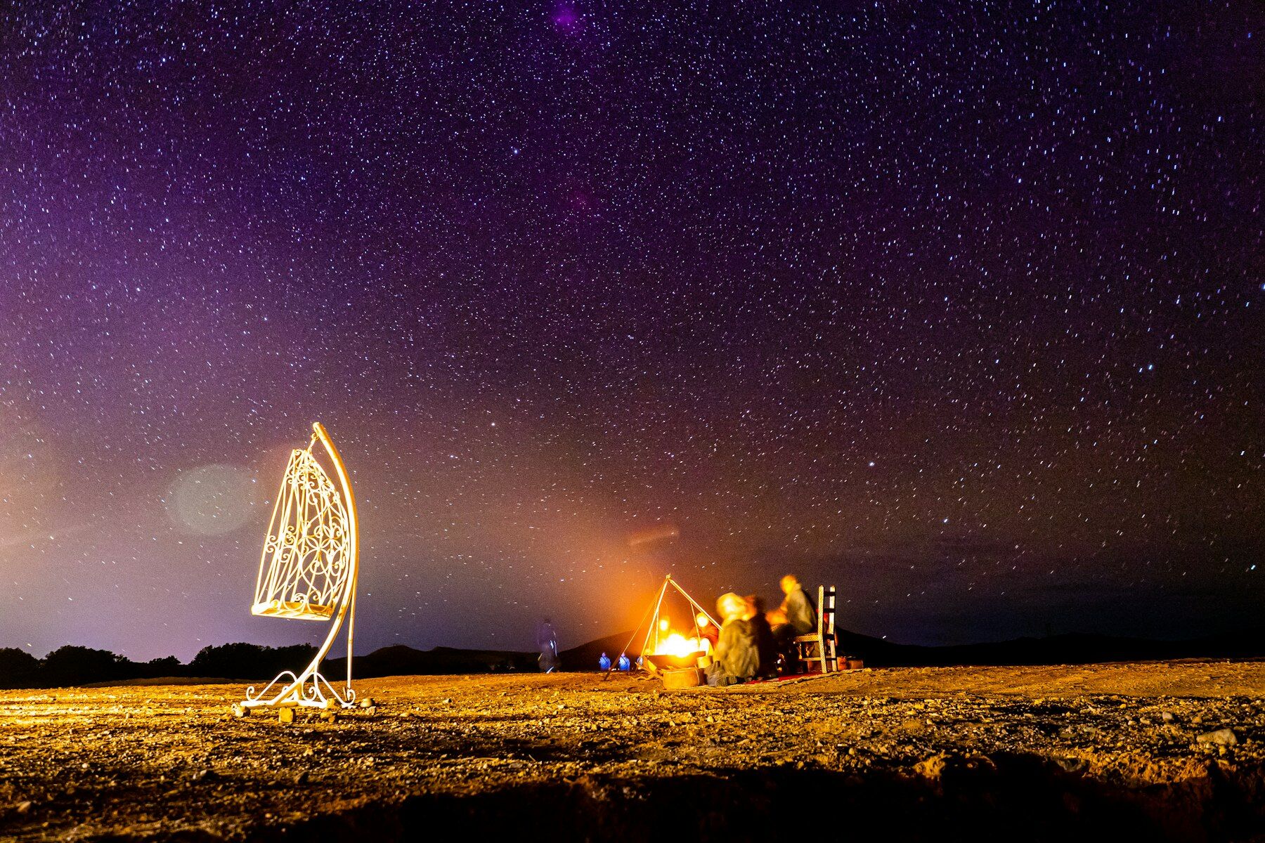 Ciel étoilé violet au-dessus d'un feu de camp et d'une lanterne marocaine dans le désert