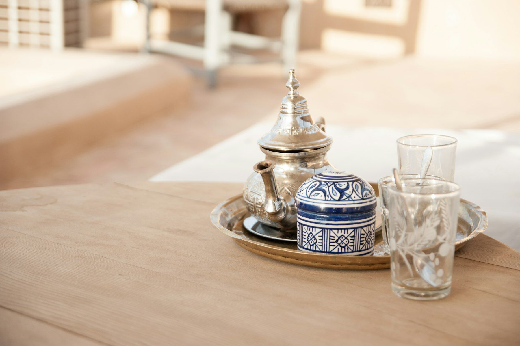 Théière argentée, sucrier bleu et blanc et verres à thé sur un plateau