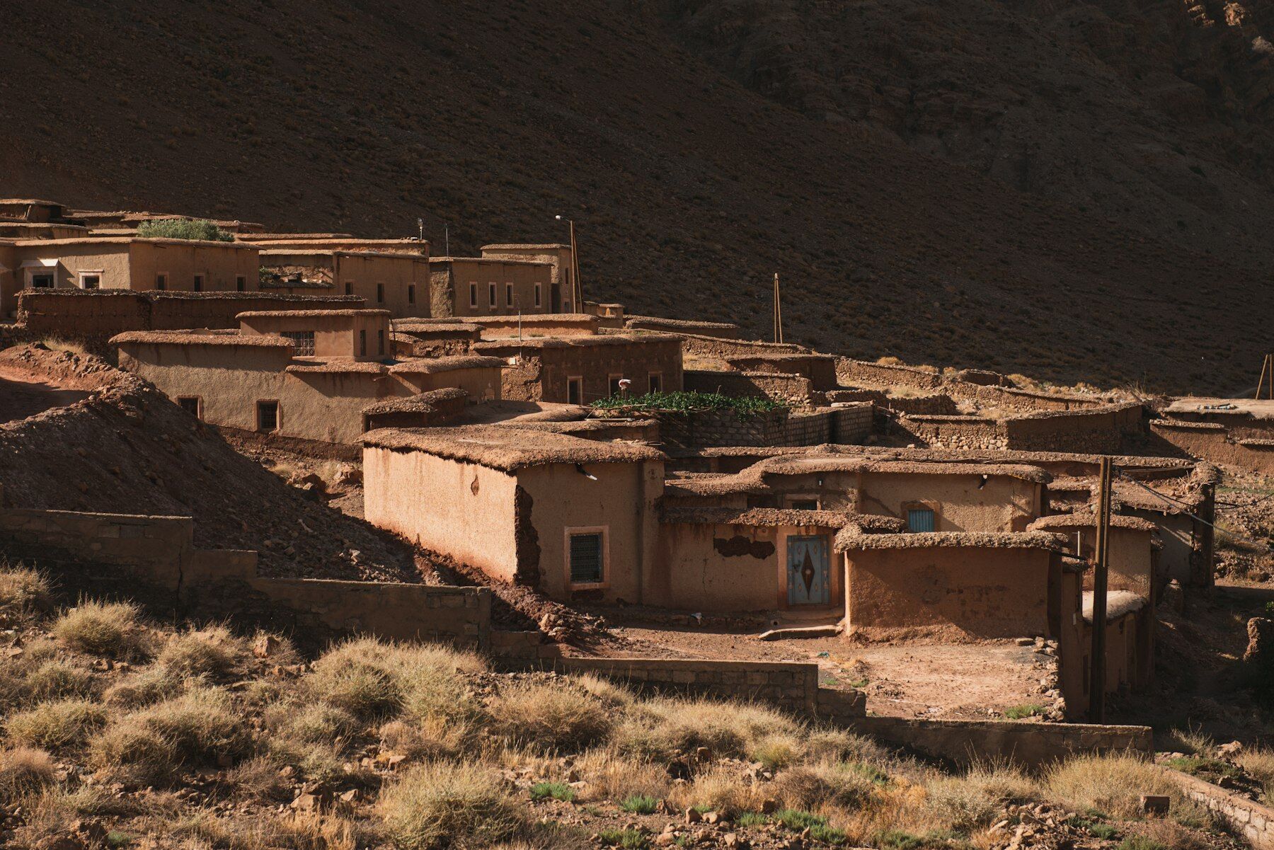 Village en pisé au pied d'une montagne, lumière de fin de journée