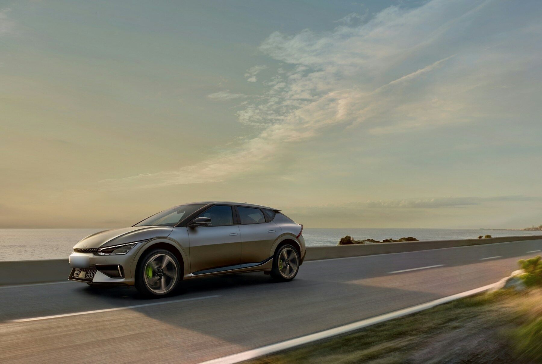 Voiture électrique grise roulant sur une route au bord de la mer