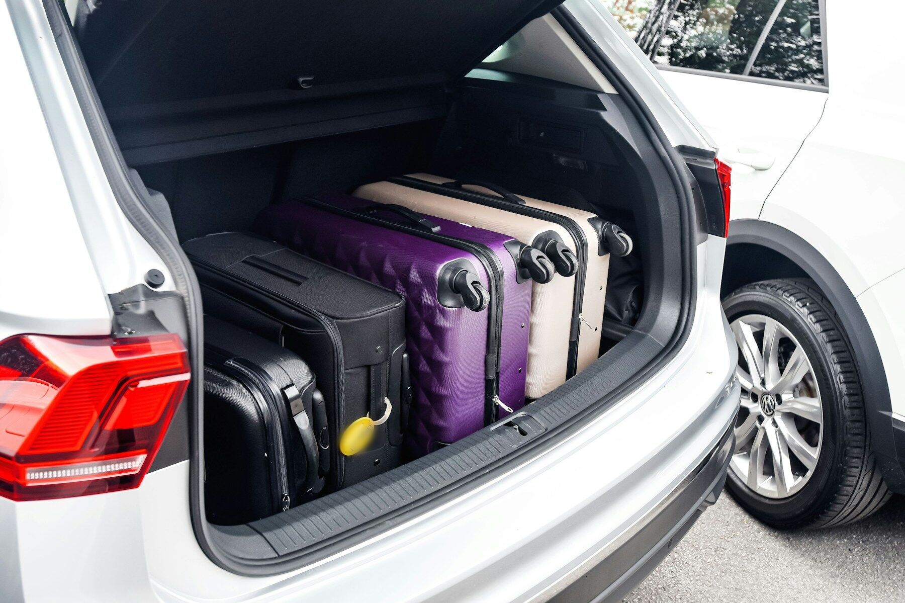 Coffre ouvert d’une voiture blanche rempli de valises