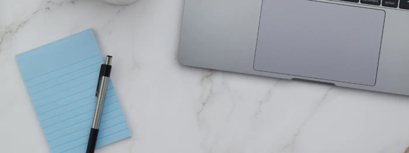 Un bureau épuré avec un ordinateur portable, un carnet et une tasse de café